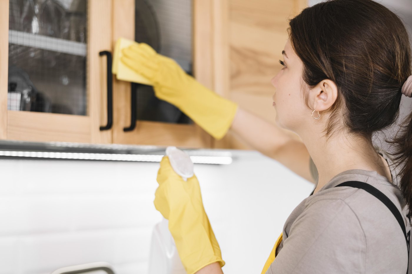Mujer limpiando los armarios de la cocina